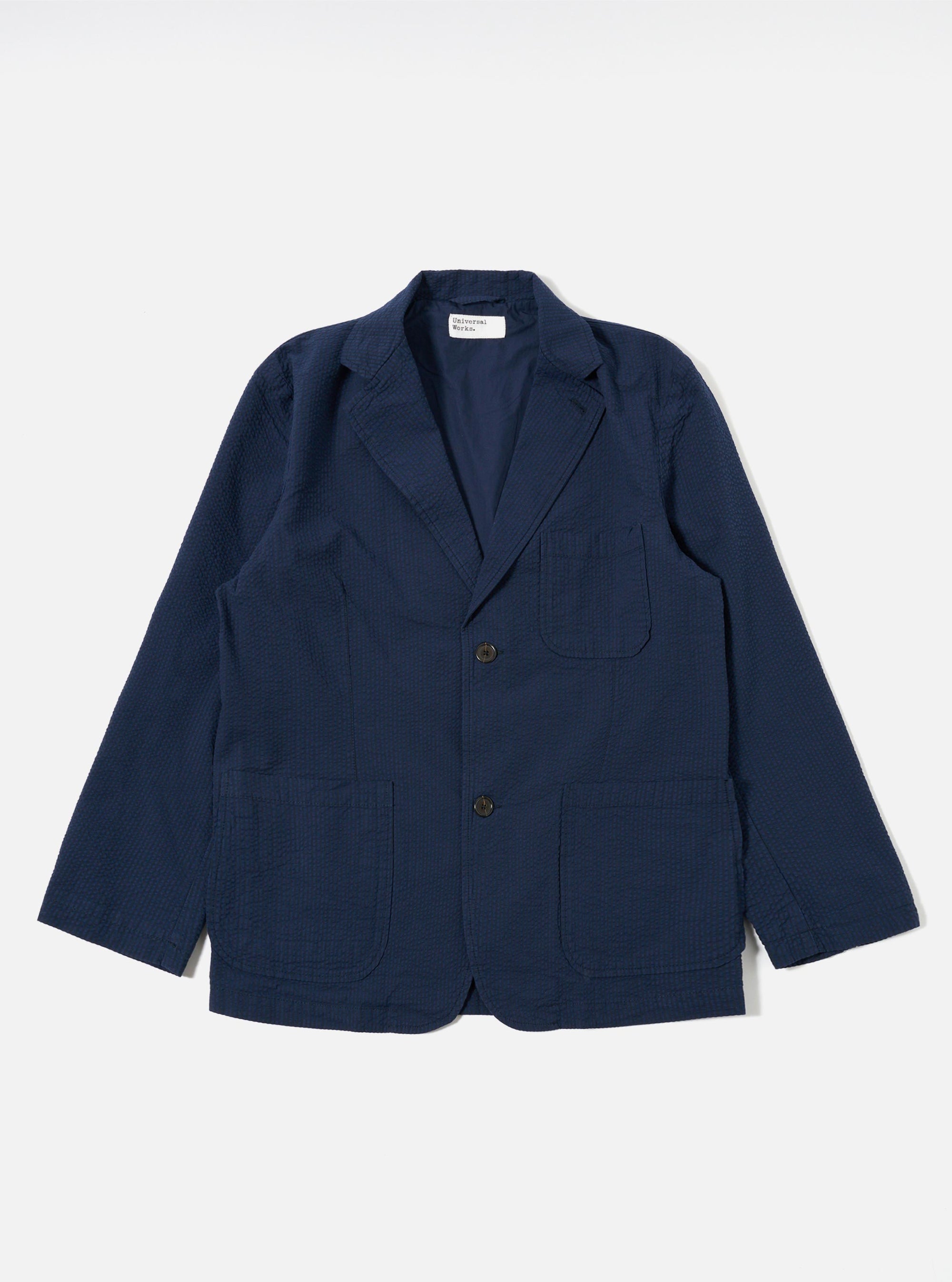 The Navy Derby Stripe Two Button Jacket is displayed as a flat lay against a white background. The jacket features notched lapels, a two-button front closure, and two large patch pockets at the waist. The fabric has a distinct navy and white vertical stripe pattern throughout.