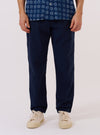 A model wears the Navy Derby Stripe Military Chino against a plain white background. The image shows a front view of the trousers, highlighting the slim, straight-leg fit and the navy blue fabric with thin vertical white derby stripes. The model is wearing the chinos with a tucked-in shirt to show the waistband and button closure.