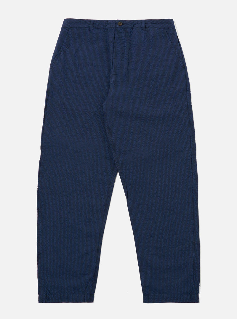 The Navy Derby Stripe Military Chino is presented as a flat lay against a plain white background. The trousers feature a straight-leg cut with a button fly, belt loops, and two slanted front pockets. The fabric is a navy blue cotton with a subtle, vertical derby stripe pattern.