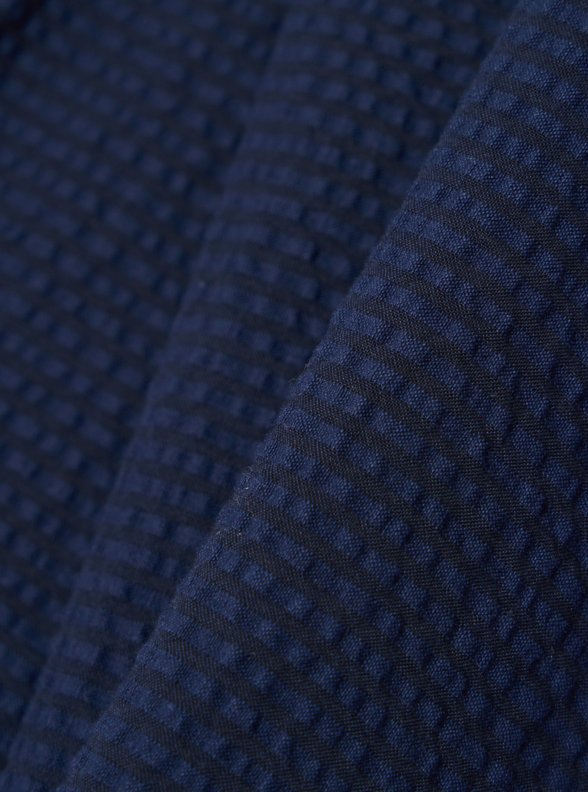 A close-up swatch image of the Navy Derby Stripe Military Chino fabric highlights the navy blue color and the distinct puckered texture of the seersucker material. The pattern features a subtle pinstripe design.