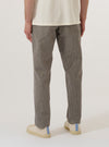 A model is wearing the Multi Lucas Cotton Mix Military Chino, shown from the waist down against a plain white background. The trousers feature a straight-leg fit and a multi-colored check pattern. The model is standing with one hand in a front pocket, showcasing the mid-rise waist, belt loops, and the texture of the cotton-mix fabric. The trousers are styled with a slight break at the hem over white sneakers.