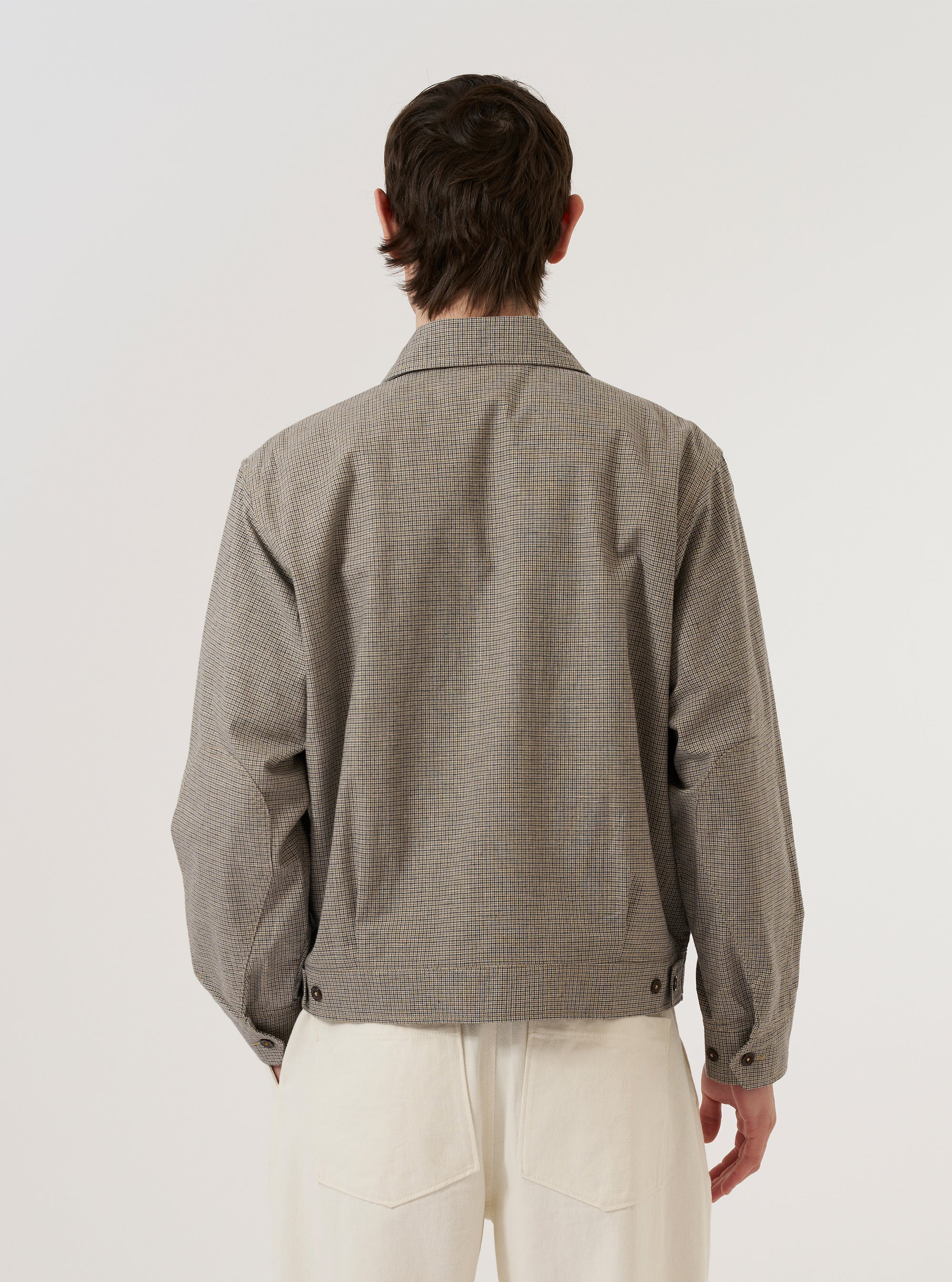 A model wears the Multi Lucas Cotton Mix E130 Jacket, shown from the back against a plain white background. The jacket features an all-over multi-colored check pattern and is crafted from a textured cotton, linen, and acrylic mix. The image highlights the garment's relaxed fit, straight hem, and structured shoulders.