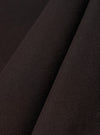 A close-up fabric swatch of the Licorice Summer Canvas Labour Jacket highlights a deep brown color and a durable, woven canvas texture. The image shows the material as a solid, flat surface with a subtle, suede-like finish.