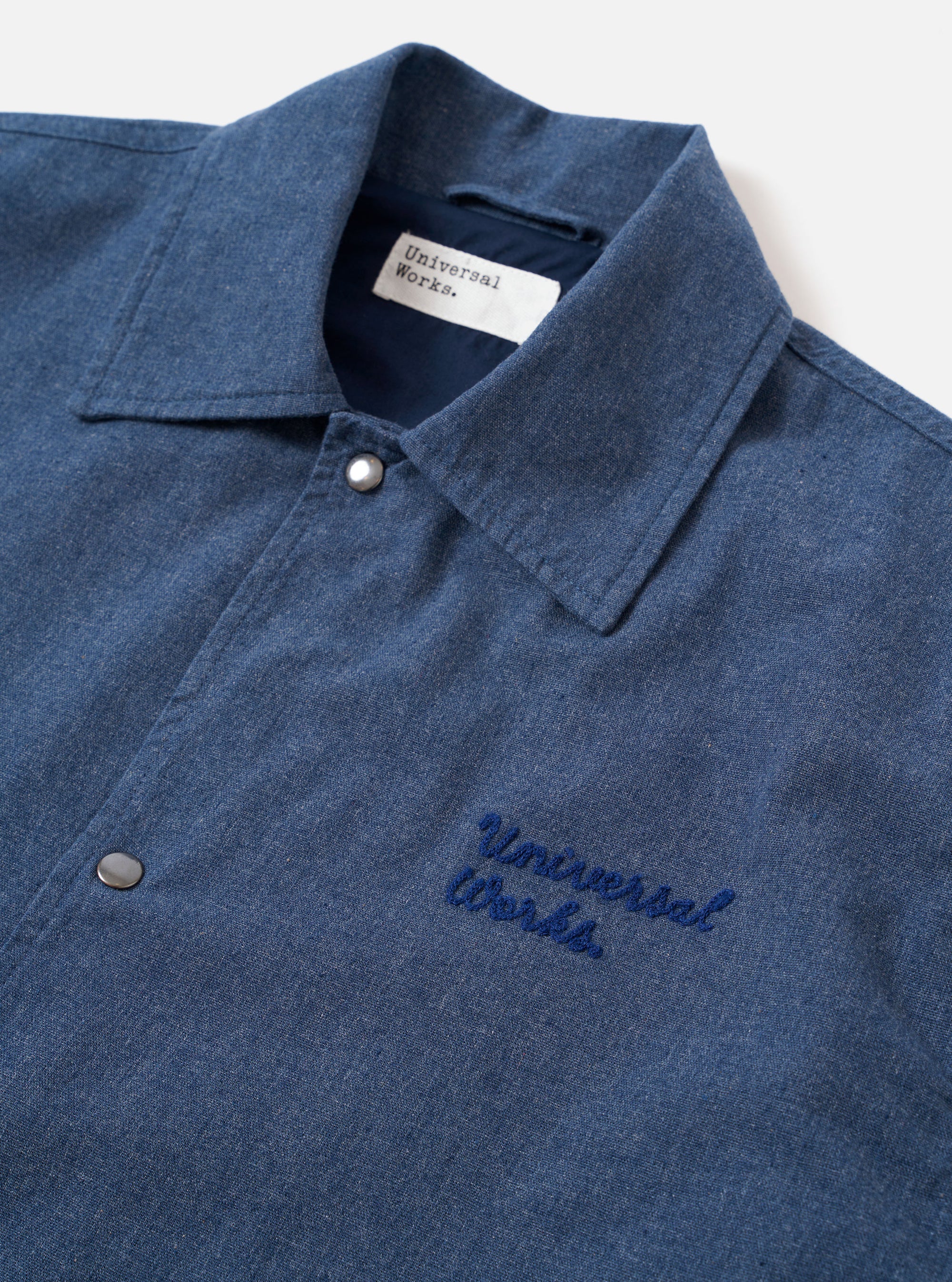 The Blue Sintra Recycled Cotton Head Coach Jacket is displayed as a flat lay against a plain white background. The jacket features a relaxed, boxy fit with a central two-way zip closure and a classic shirt-style collar. Two prominent patch pockets with buttoned flaps are positioned on the chest, accompanied by two slanted handwarmer pockets at the waist. The garment is constructed from a solid blue recycled cotton fabric with a visible weave.