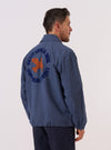 A model wears the Blue Sintra Recycled Cotton Head Coach Jacket over a light-colored top, shown from a side-angle view against a plain white background. The jacket features a classic pointed collar, a central button-down closure, and a straight hem. The garment is constructed from a blue recycled cotton and polyester blend fabric with a smooth, durable finish.