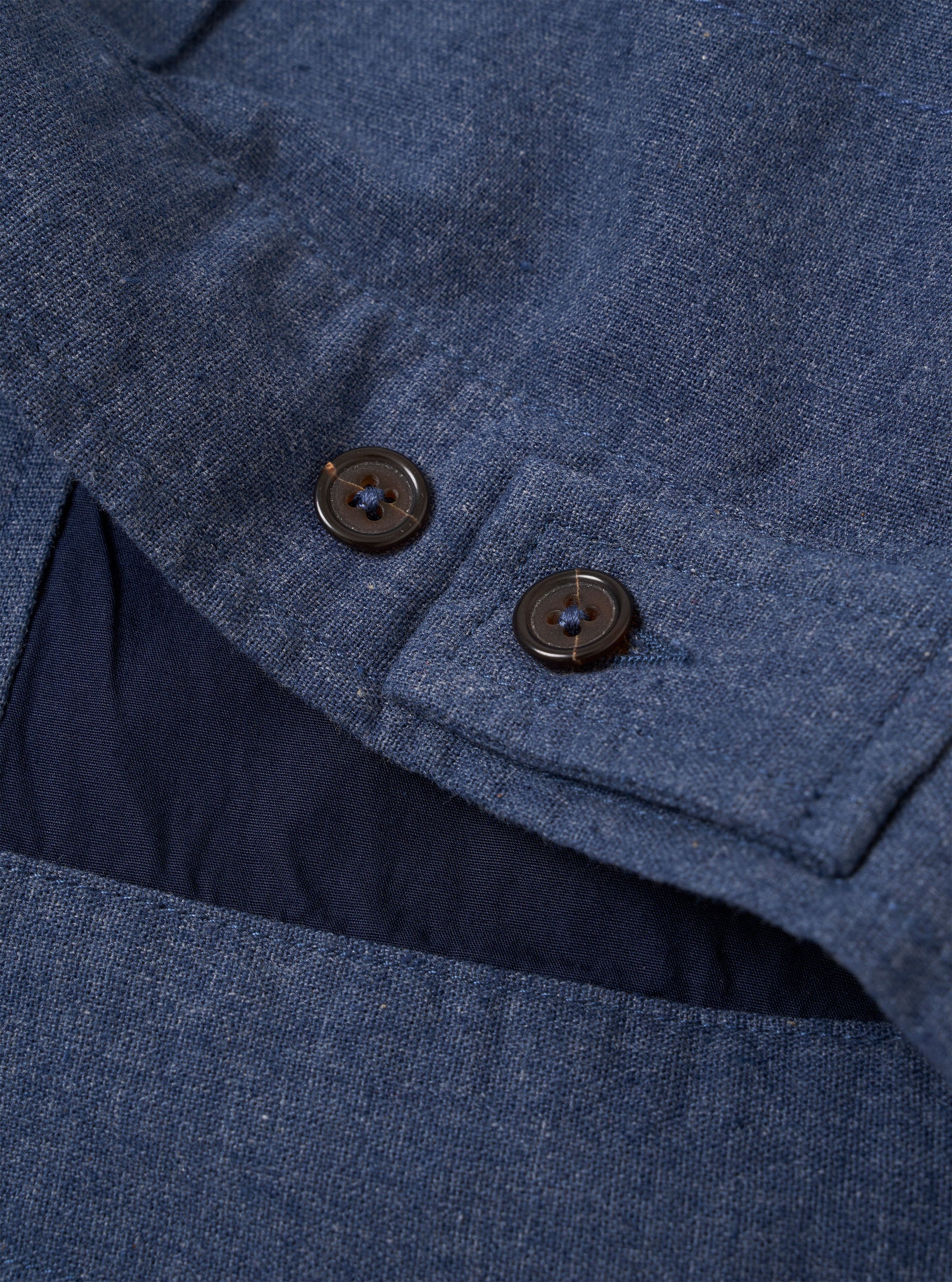 The Blue Sintra Recycled Cotton E130 Jacket is shown in a detail view as a flat lay against a plain white background. The image highlights the jacket's two-way zip front, structured collar, and the texture of the blue recycled cotton fabric. The top of a front button-flap pocket is also visible.