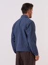 A model wears the Blue Sintra Recycled Cotton E130 Jacket, shown from the back against a plain white background. The jacket features a clean-cut back panel, a structured collar, and a straight hem. The garment is made from a solid blue recycled cotton fabric with a smooth finish.