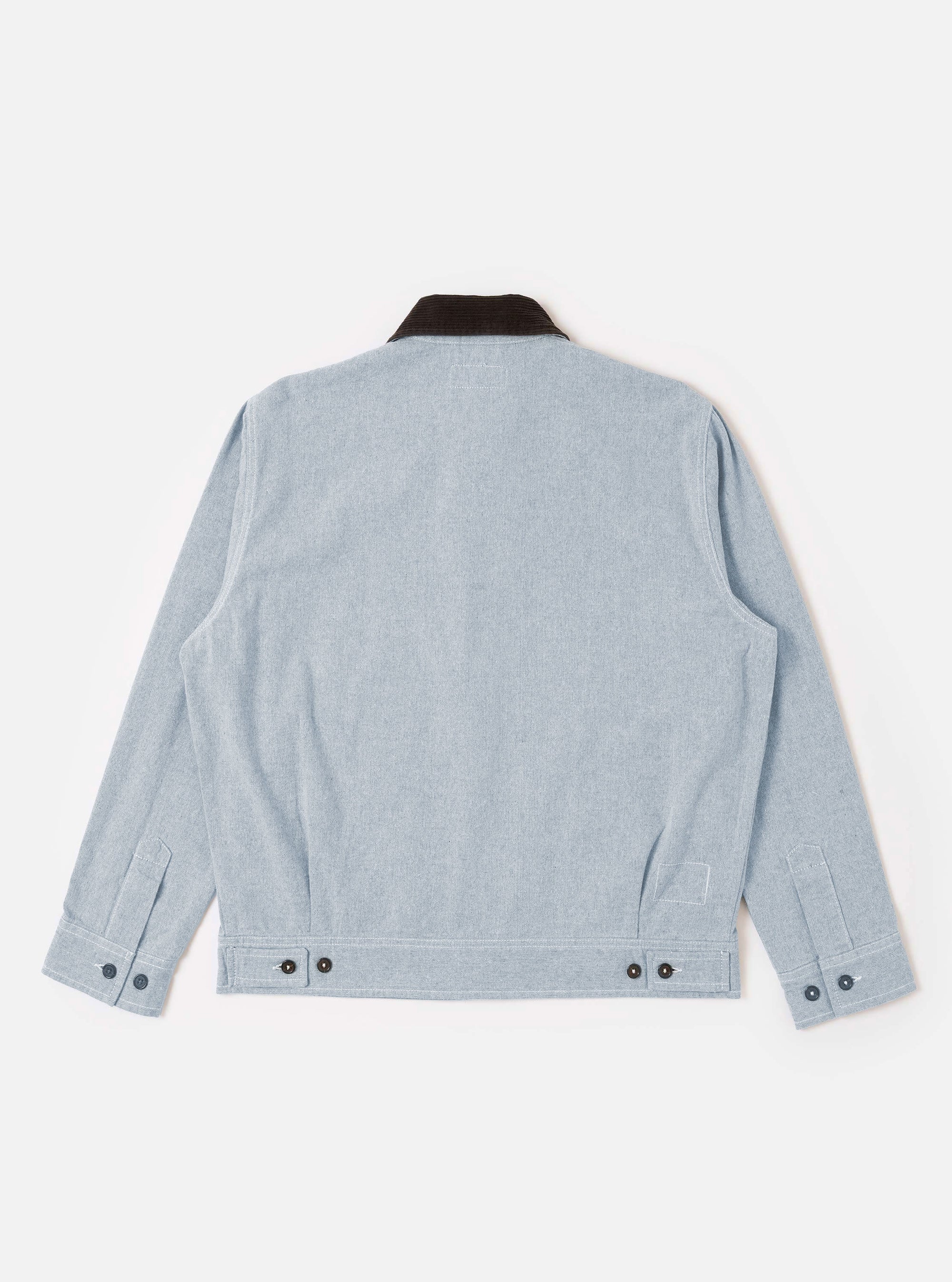The Light Indigo Jean Cloth Reworked Rose Bowl Jacket is shown from the back as a flat lay against a plain white background. The image highlights the boxy fit, the slightly oversized collar, and the adjustable back hem with buttoned tabs. The light indigo organic cotton fabric features a subtle textured finish.