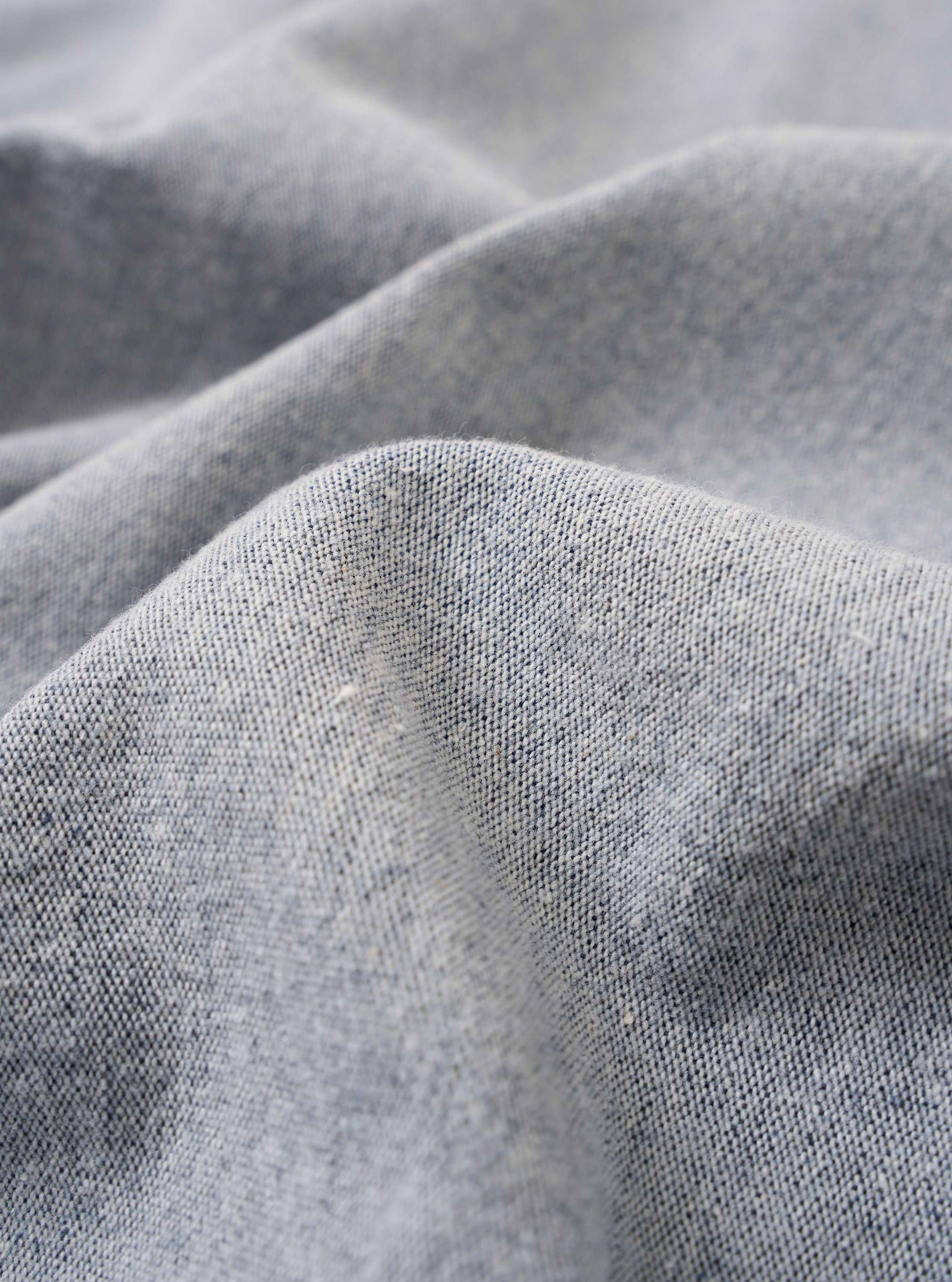 A close-up fabric swatch of the Light Indigo Jean Cloth Reworked Rose Bowl Jacket highlights the light indigo blue color and the textured weave of the reworked jean cloth material.