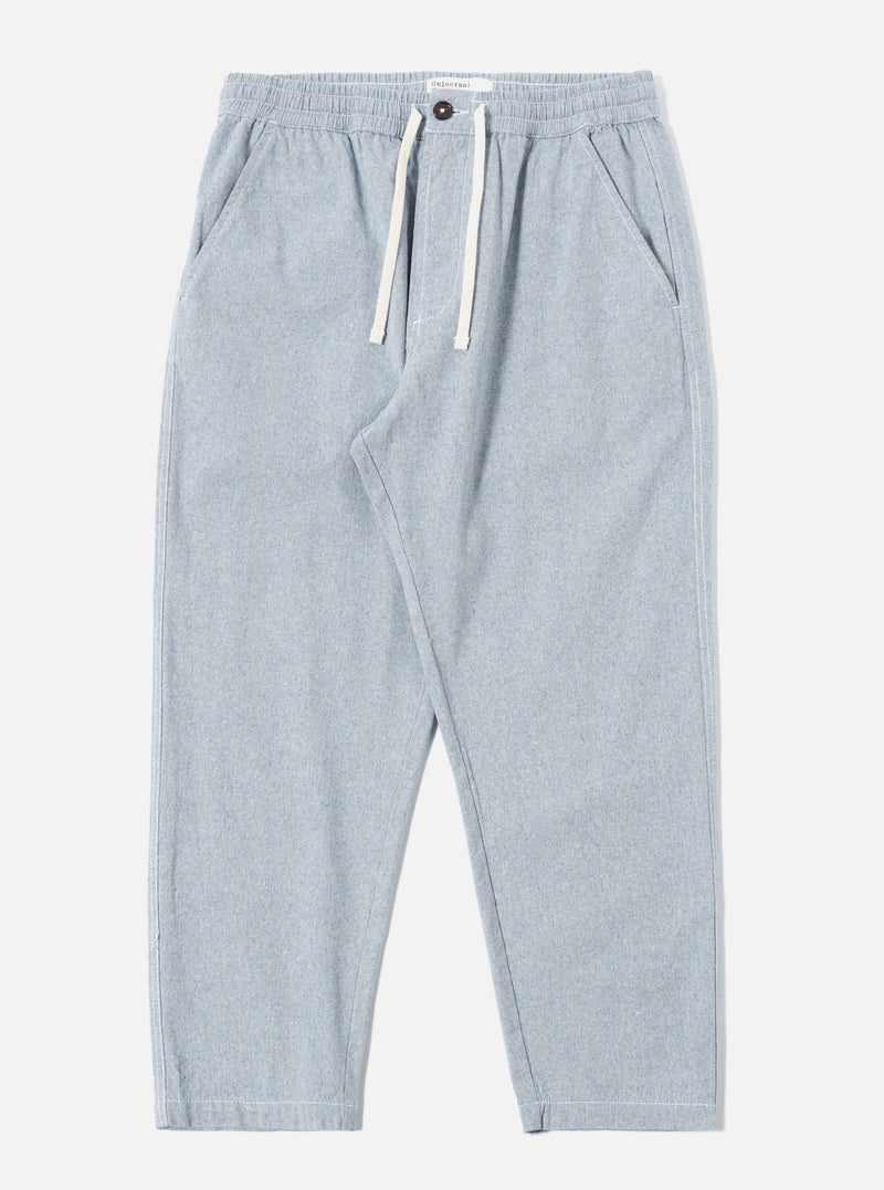 The Light Indigo Jean Cloth Reworked Hi Water Trouser is shown as a flat lay against a white background. The trousers feature a drawstring waist, two slanted front pockets, and a slightly cropped, loose fit. The fabric is a light indigo organic cotton with a visible textured weave.
