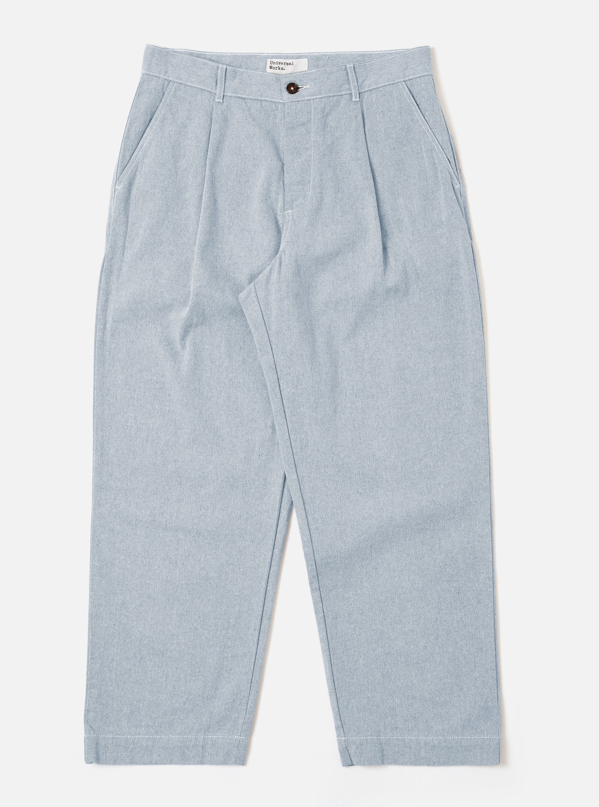 The Light Indigo Jean Cloth Reworked Duke Pant is shown as a flat lay against a plain white background. The trousers feature a wide-leg fit, a single pleat at the front, and a button-front closure with a fixed waistband. The light indigo organic cotton fabric has a textured appearance.