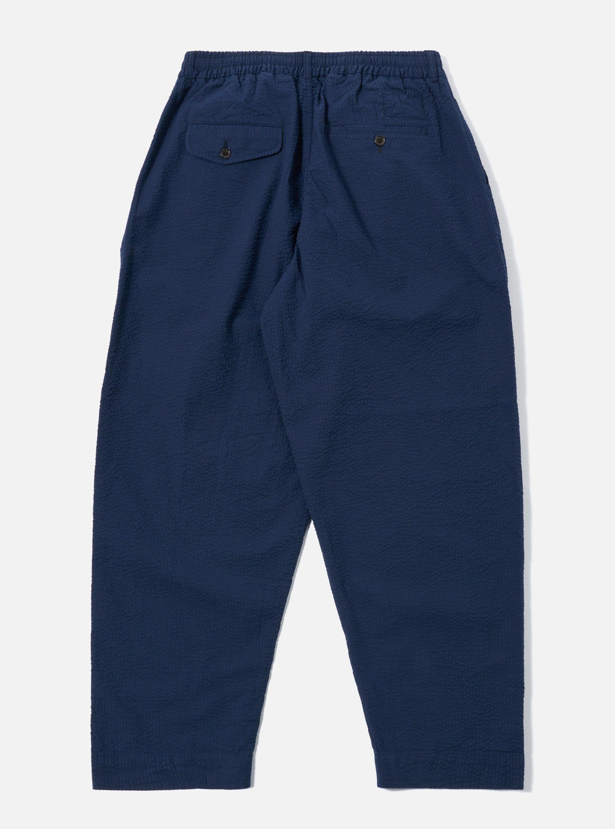 The Navy Derby Stripe Oxford Pant is shown from the back as a flat lay against a plain white background. The image highlights the two rear patch pockets, an elasticated waistband with a drawstring, and a subtle vertical stripe pattern on the navy cotton fabric.