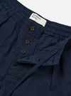 The Navy Derby Stripe Oxford Pant is shown in a detail view as a flat lay against a plain white background. The image highlights the construction of the waistband, featuring an internal drawstring and front pleats. The cotton fabric displays a distinct navy and white vertical derby stripe pattern with visible textured stitching.