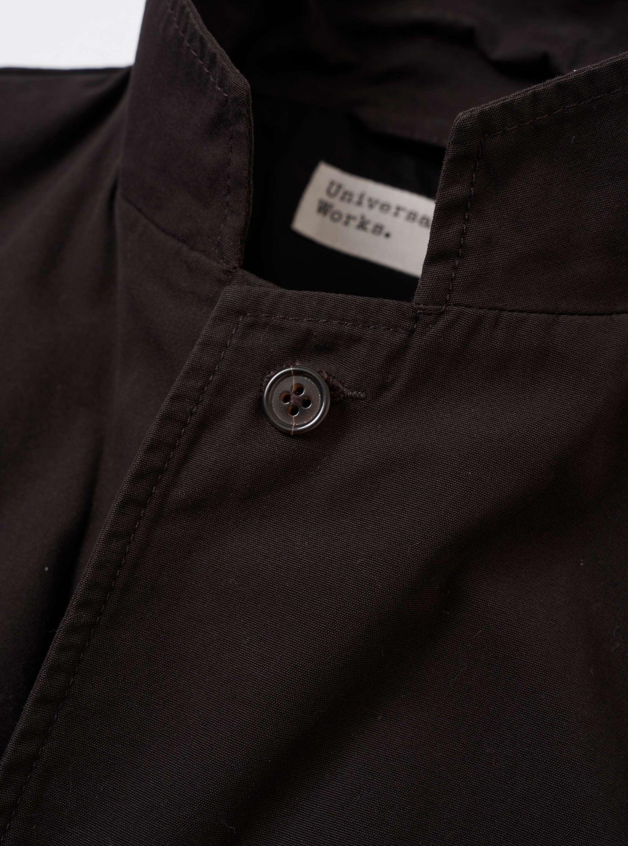 The Licorice Summer Canvas Two Button Jacket is displayed as a flat lay against a solid white background. The brown jacket features a notched lapel, a two-button front closure, and three patch pockets, including one on the chest and two larger ones at the waist. The cotton canvas fabric has a visible weave and structured appearance.