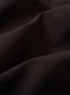 A close-up fabric swatch of the Licorice Summer Canvas Two Button Jacket highlights the dark brown, licorice-colored cotton canvas. The image provides a detailed view of the material's weave and slightly textured, suede-like surface.
