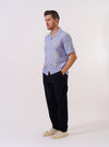 The Blue Oxford Shirting Road Trip Shirt is shown as a flat lay against a plain white background. The shirt features a camp collar, a full button-down front with tonal buttons, and a straight hem. The blue Oxford cloth has a visible textured weave.