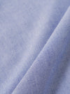 A close-up fabric swatch of the Blue Oxford Shirting Road Trip Shirt shows the detailed texture of the blue Oxford cotton material. The image displays the characteristic weave of blue and white threads.
