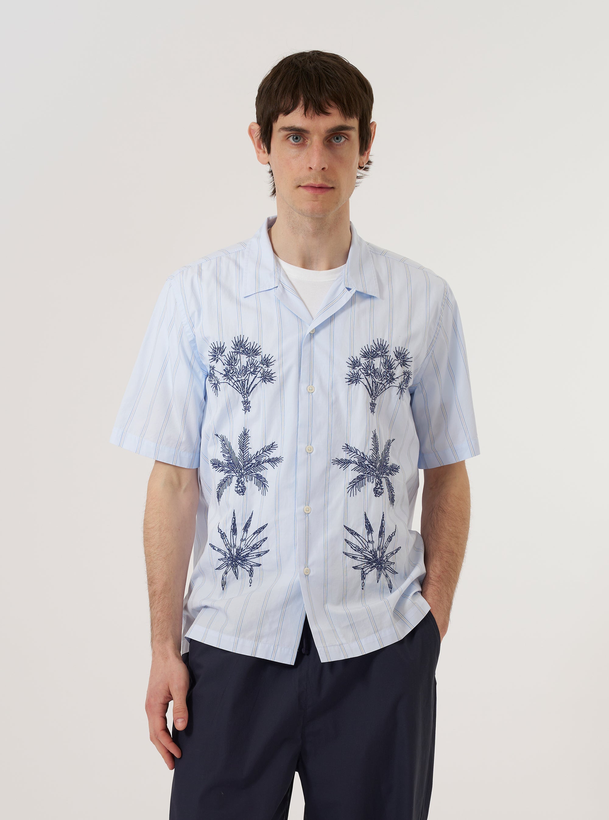 A model wears the Soft Blue Mc Stripe Road Trip Shirt against a plain white background. The shirt features a camp collar, a button-down front, and a vertical striped pattern in shades of blue and white. The model is shown from the chest up, highlighting the shirt's collar and shoulder fit.