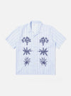The Soft Blue Mc Stripe Road Trip Shirt is displayed as a flat lay against a plain white background. The shirt features a camp collar, a chest patch pocket, and a full button-down front. The fabric has a distinctive vertical stripe pattern in shades of blue and white.