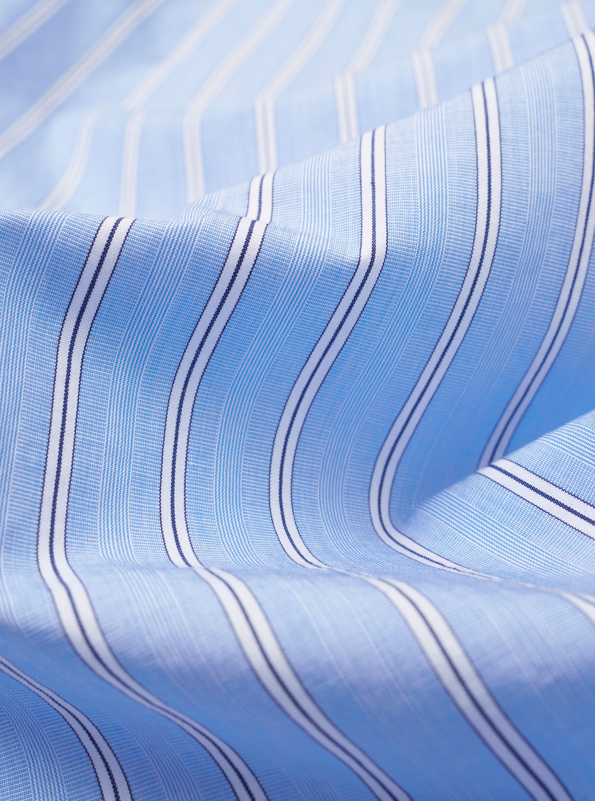The Blue Mc Stripe Square Pocket Shirt is shown from a rear angle as a flat lay against a plain white background. The image highlights the shirt's back yoke, curved hem, and the fine vertical blue and white stripe pattern of the cotton fabric.