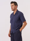 A model wears the Navy Sido Linen Mix Road Shirt over a white t-shirt, standing against a plain white background. The navy blue shirt features a camp collar, a single chest patch pocket, and a full button-down front. The garment is shown from a front-facing view in a studio setting.