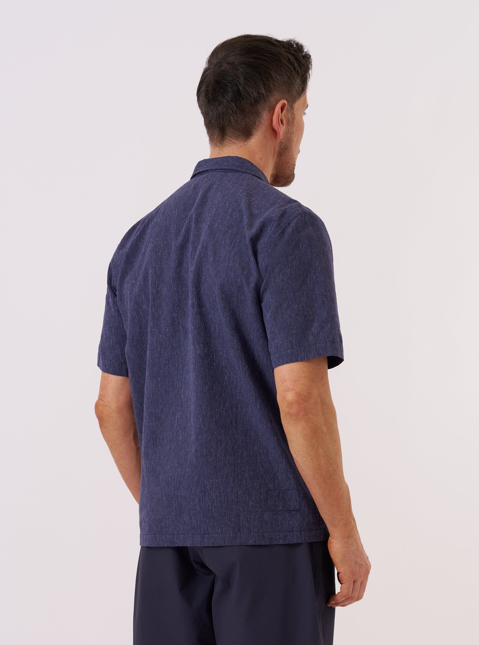 A model wears the Navy Sido Linen Mix Road Shirt, shown from the back against a plain white background. The shirt features short sleeves, a straight hem, and a structured one-piece collar. The fabric is a dark navy blue cotton-linen blend with a subtle textured finish.