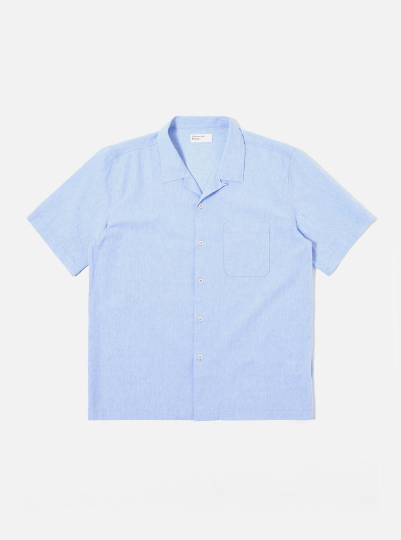 The Sky Blue Sido Linen Mix Road Shirt is shown as a flat lay against a plain white background. The shirt features a camp collar, a central button-down front with tonal buttons, and a single patch pocket on the left chest. The fabric is a lightweight sky blue cotton-linen blend with a subtle texture.