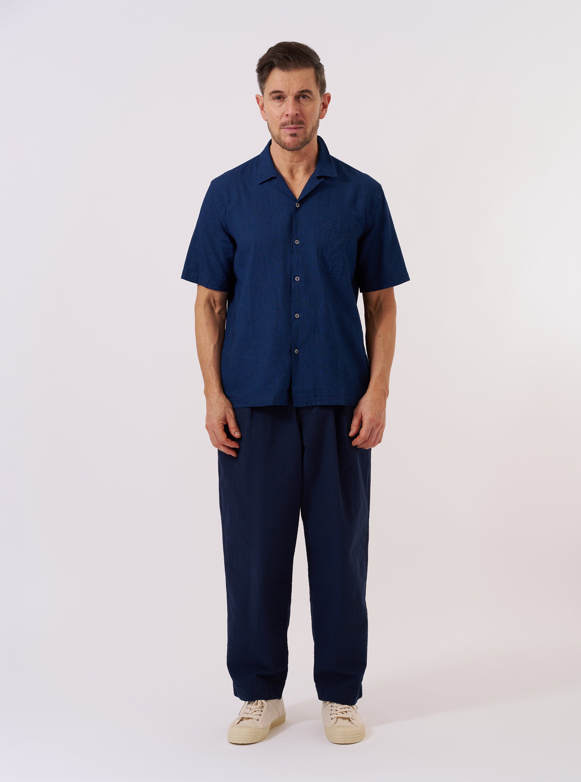 The Indigo Lincot Denim Road Shirt is shown as a flat lay against a white background. The shirt features a camp collar, a single chest patch pocket on the left side, and a full button-down front with light-colored buttons. The fabric is a dark indigo denim with visible stitching details.