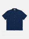 The Indigo Lincot Denim Road Shirt is presented as a flat lay against a plain white background. The short-sleeved shirt features a camp collar, a six-button front closure with contrasting white buttons, and a single patch pocket on the left chest. The indigo-dyed fabric shows a fine denim texture from the cotton and linen blend.
