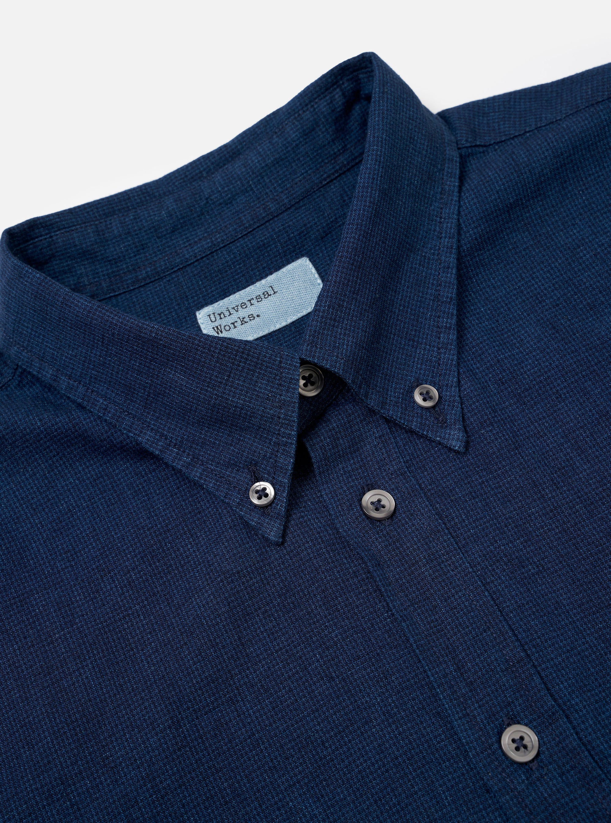 The Indigo Lincot Denim Lazy Day Shirt is shown from the back as a flat lay against a plain white background. The image highlights the back yoke and a central box pleat, which adds volume to the relaxed fit. The shirt is made from a dark indigo cotton-linen blend denim with visible stitching along the seams and hem.