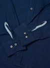 The Indigo Lincot Denim Lazy Day Shirt is shown from the back as a flat lay against a plain white background. The image highlights the back yoke with a central box pleat and the simple, straight-cut hem of the garment. The indigo-colored denim fabric, made from a cotton and linen blend, has a visible, slightly textured weave.