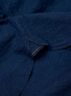 The Indigo Lincot Denim Lazy Day Shirt is shown from a rear angle as a flat lay against a plain white background. The image highlights the back yoke, a central box pleat, and the curved hem of the garment. The fabric is a dark indigo denim with visible stitching details.