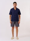 The Navy Arten Seersucker Road Shirt is displayed as a flat lay against a plain white background. The shirt features a short-sleeved design with a camp collar, a full button-down front, and a single patch pocket on the left chest. The navy organic cotton fabric has a distinct puckered seersucker texture throughout.