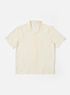 The Ecru Arten Seersucker Road Shirt is shown as a flat lay against a plain white background. The short-sleeve shirt features a camp collar with a loop-close button detail, a central button-down front, a single chest patch pocket, and a straight hem. The ecru-colored fabric has a distinct puckered seersucker texture.