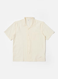 The Ecru Arten Seersucker Road Shirt is shown as a flat lay against a plain white background. The short-sleeve shirt features a camp collar with a loop-close button detail, a central button-down front, a single chest patch pocket, and a straight hem. The ecru-colored fabric has a distinct puckered seersucker texture.