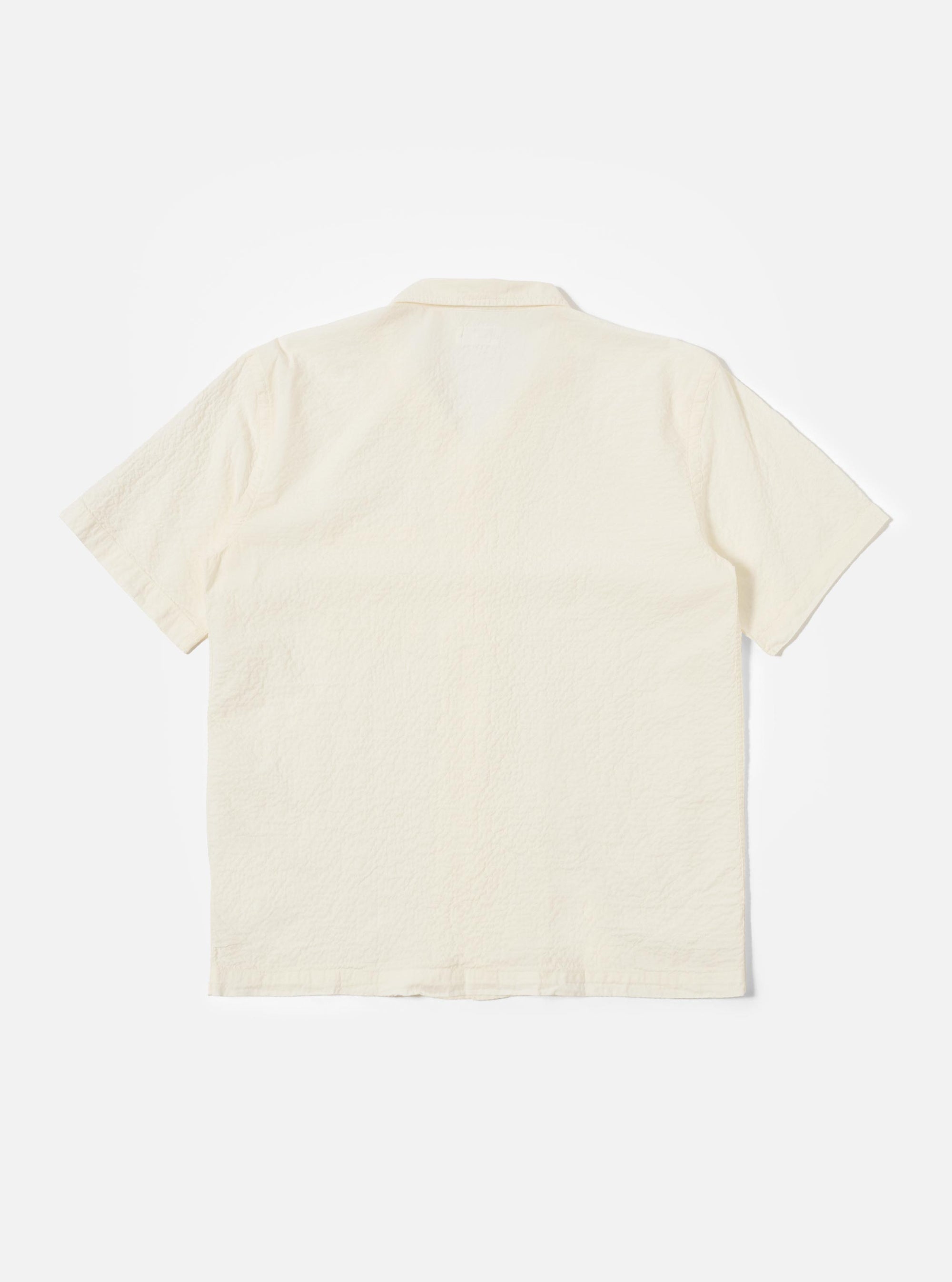 The Ecru Arten Seersucker Road Shirt is shown from the back as a flat lay against a plain white background. The image highlights the shirt's straight hem, short sleeves, and the distinct puckered texture of the ecru seersucker fabric. A clean horizontal yoke is visible across the shoulders.