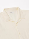 The Ecru Arten Seersucker Road Shirt is shown from the back as a flat lay against a plain white background. The image highlights the shirt's straight hem, short sleeves, and the distinct puckered texture of the ecru seersucker fabric.