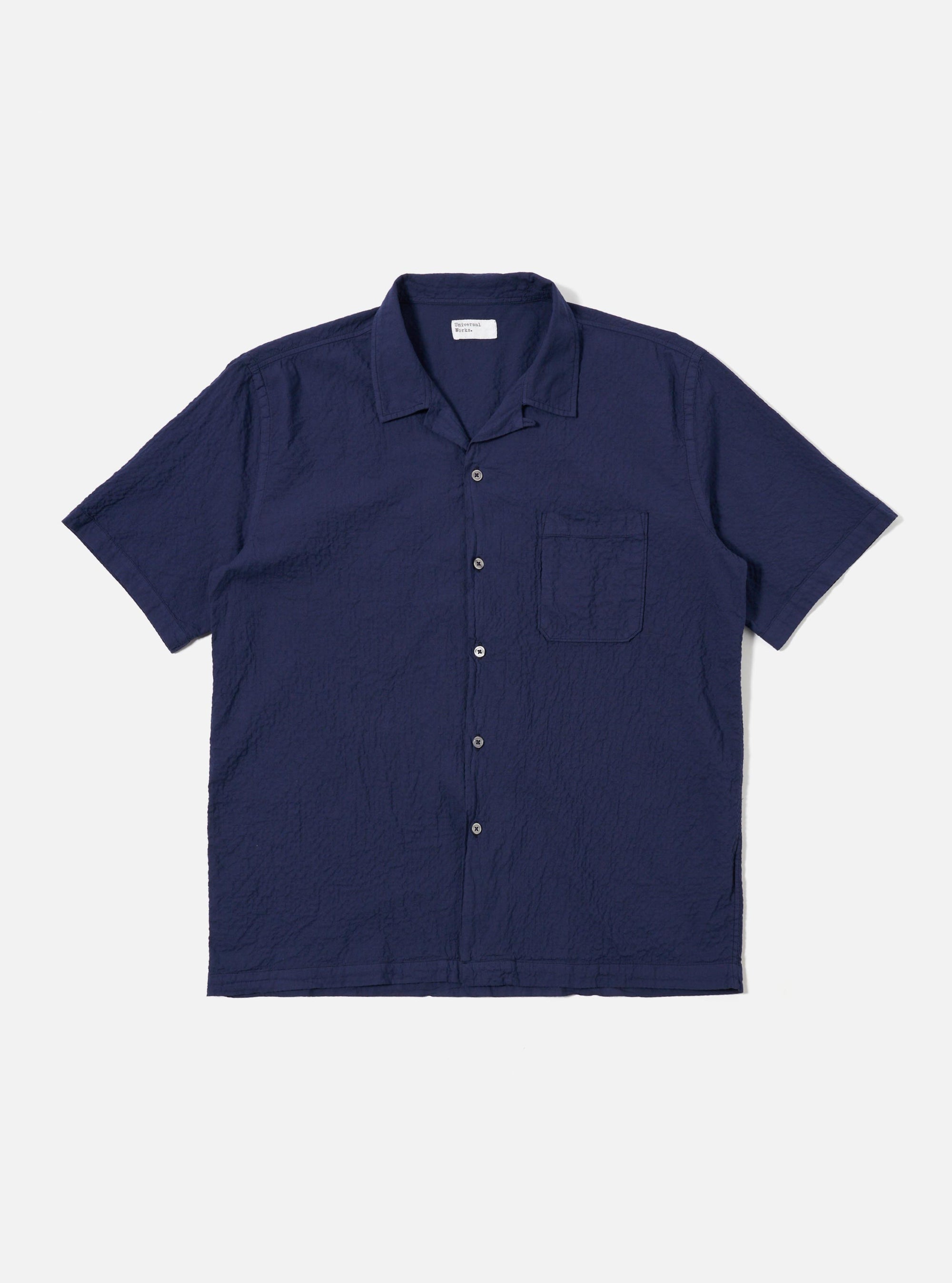 The Navy Arten Seersucker Road Shirt is shown as a flat lay against a white background. The short-sleeved shirt features a camp collar with a loop closure, a single chest patch pocket, and a straight hem. The dark navy fabric has a distinct puckered seersucker texture throughout.