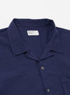 The Navy Arten Seersucker Road Shirt is shown from the back as a flat lay against a plain white background. The image highlights the garment's simple construction, featuring a straight hem, short sleeves, and a clean back panel. The navy blue organic cotton fabric exhibits a distinct puckered seersucker texture throughout.