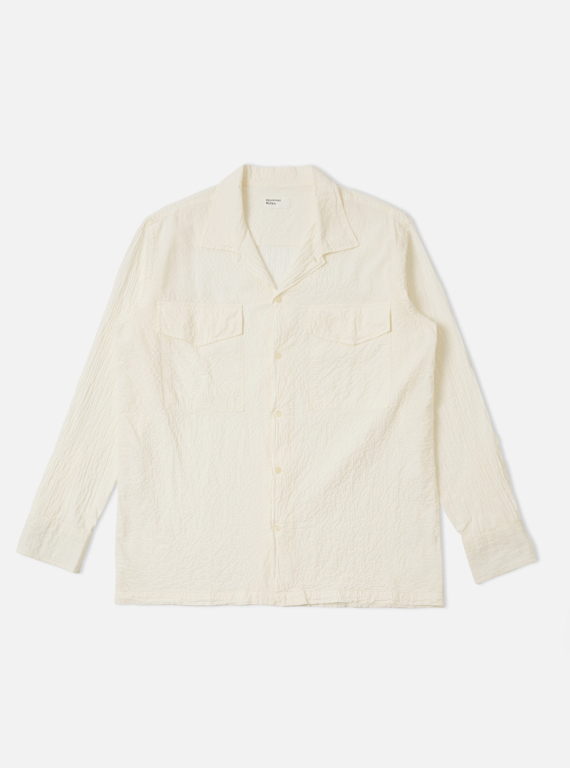 The Ecru Arten Seersucker Attendant Shirt is shown as a flat lay against a plain white background. The shirt features a button-through front, two chest patch pockets with flaps, and a structured collar. The ecru fabric has a distinct puckered seersucker texture.