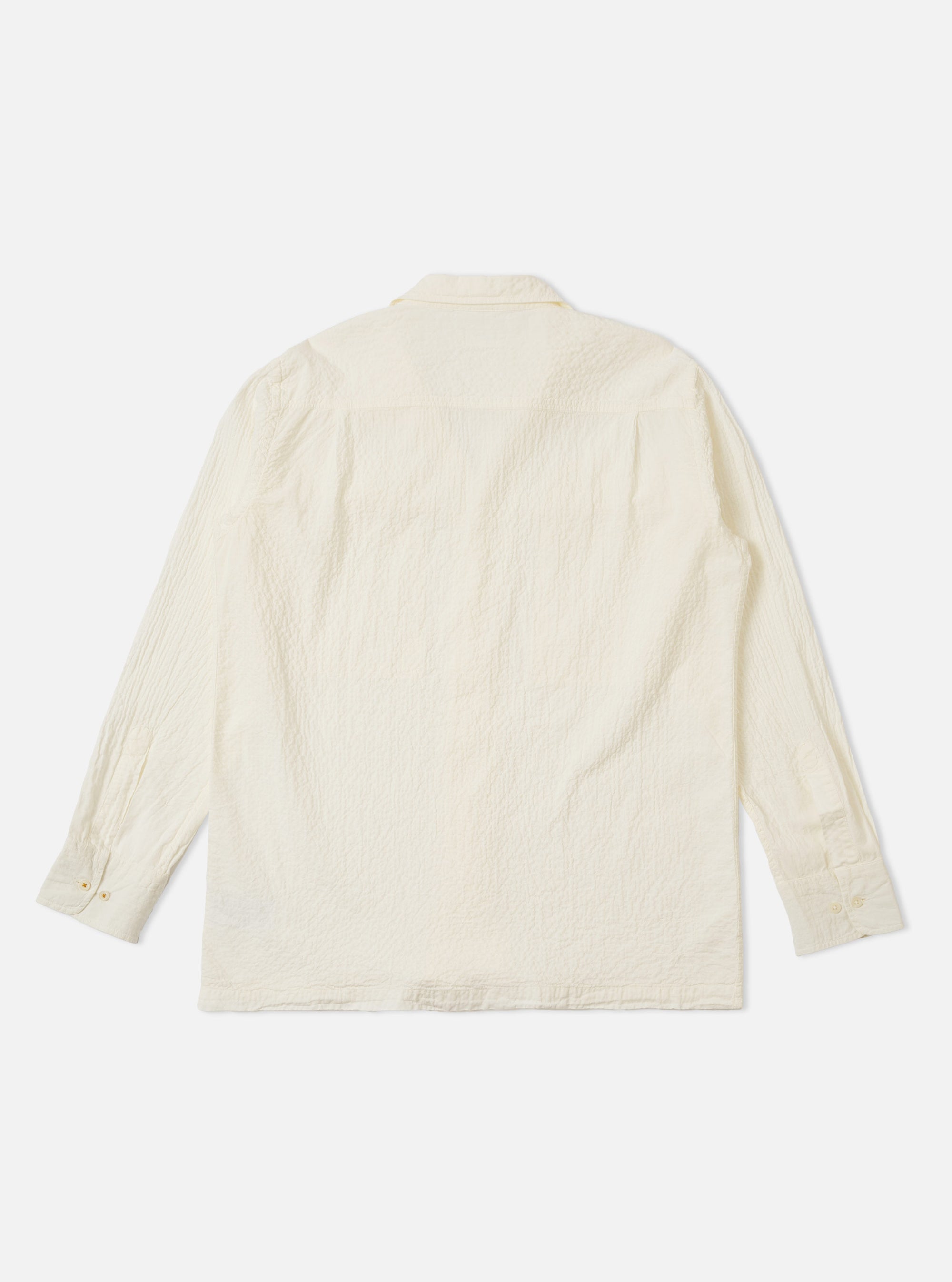 The Ecru Arten Seersucker Attendant Shirt is shown from the back as a flat lay against a plain white background. The image highlights the puckered texture of the ecru seersucker fabric and the simple, straight-cut construction of the rear panel.