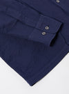The Navy Arten Seersucker Attendant Shirt is shown from a rear three-quarter angle as a flat lay against a plain white background. The image highlights the shirt's straight hem, side vents, and the textured navy blue seersucker fabric with its characteristic puckered finish.