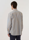 A model wears the Multi Pop Multi Stripe Square Pocket Shirt, shown from the back against a plain white background. The shirt features a bold vertical multi-stripe pattern in various colors throughout the fabric. The image highlights the straight-cut back panel and the continuation of the stripe design across the shoulders and sleeves. The model is shown from the waist up, emphasizing the garment's relaxed fit.