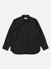 The Black Tropical Suiting Travail Overshirt is shown as a flat lay against a white background. The overshirt features a one-piece collar, a central button-down closure, and two large patch pockets at the waist. The lightweight black tropical suiting fabric has a smooth, minimal appearance.