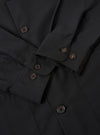 The Black Tropical Suiting Travail Overshirt is shown in a detail view as a flat lay against a plain white background. The image focuses on the lower front section of the garment, highlighting the smooth texture of the black tropical suiting fabric, the straight hem, and the clean stitching of a large patch pocket.