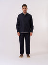The Navy Tropical Suiting Travail Overshirt is shown as a flat lay against a white background. The overshirt features a single-piece collar, a button-through front, and two large patch pockets at the waist. The navy blue tropical wool fabric has a smooth, lightweight appearance with a curved hem.
