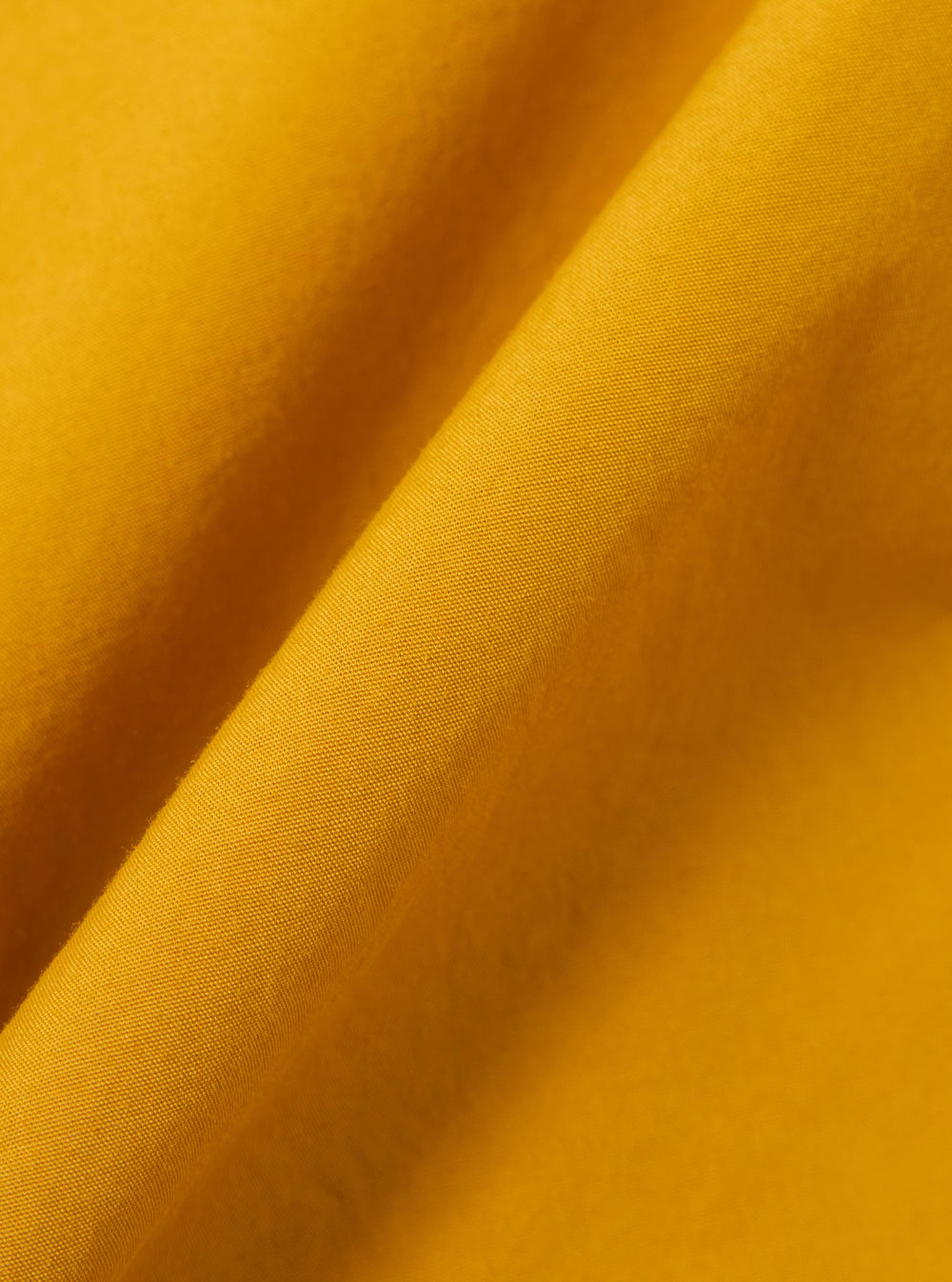 A close-up swatch image of the Golden Brown Organic Fine Poplin CPO Shirt fabric. The image focuses on the golden brown color and the smooth, tightly woven texture of the organic cotton poplin material.