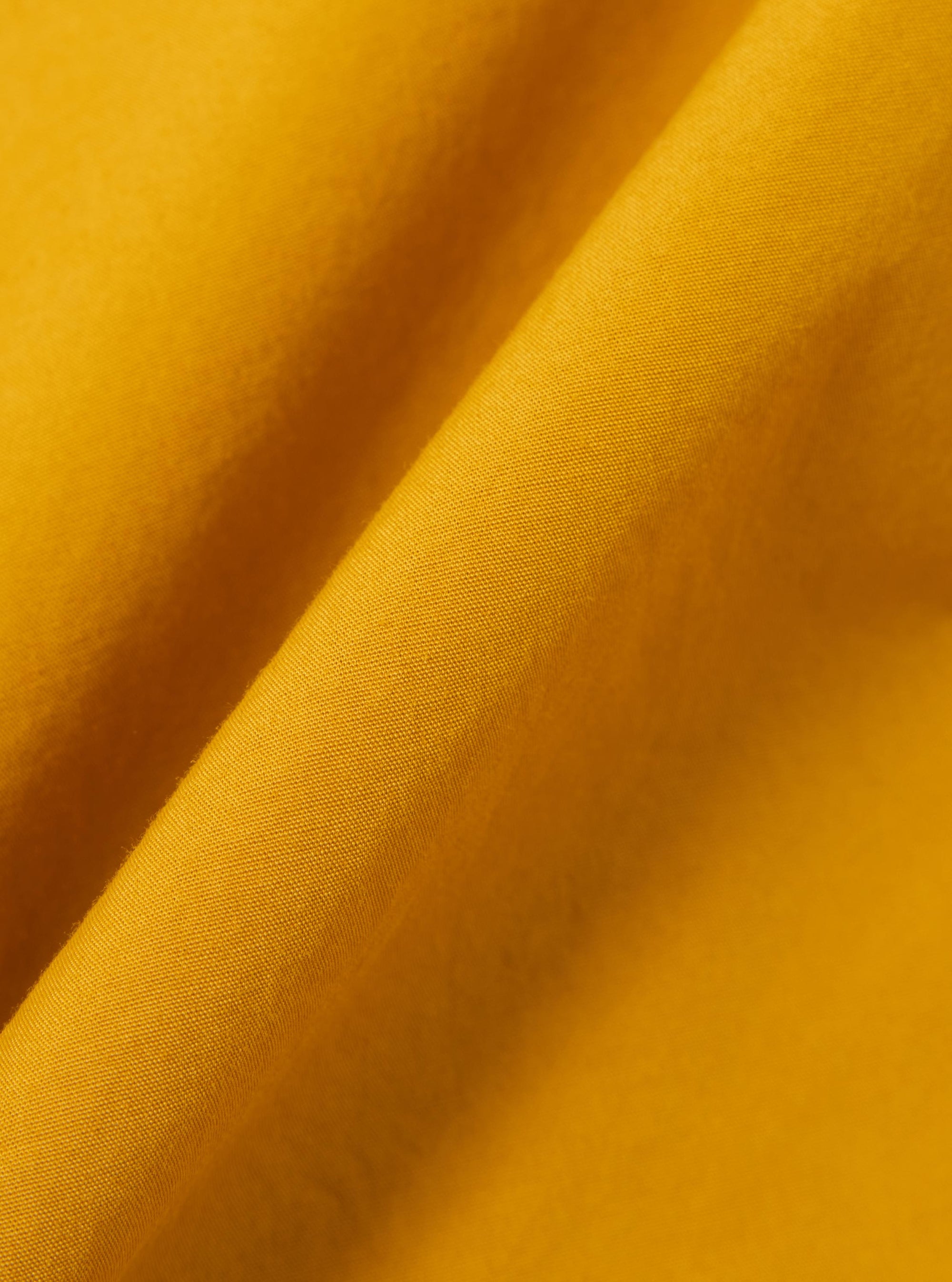 A close-up swatch image of the Golden Brown Organic Fine Poplin CPO Shirt fabric. The image focuses on the golden brown color and the smooth, tightly woven texture of the organic cotton poplin material.
