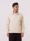 A model wears the Ecru Koko Cotlin Smock Overshirt against a plain white background. The garment features a pullover design with a partial button placket, a classic collar, and is made from a textured cotton-linen fabric in an off-white ecru shade.