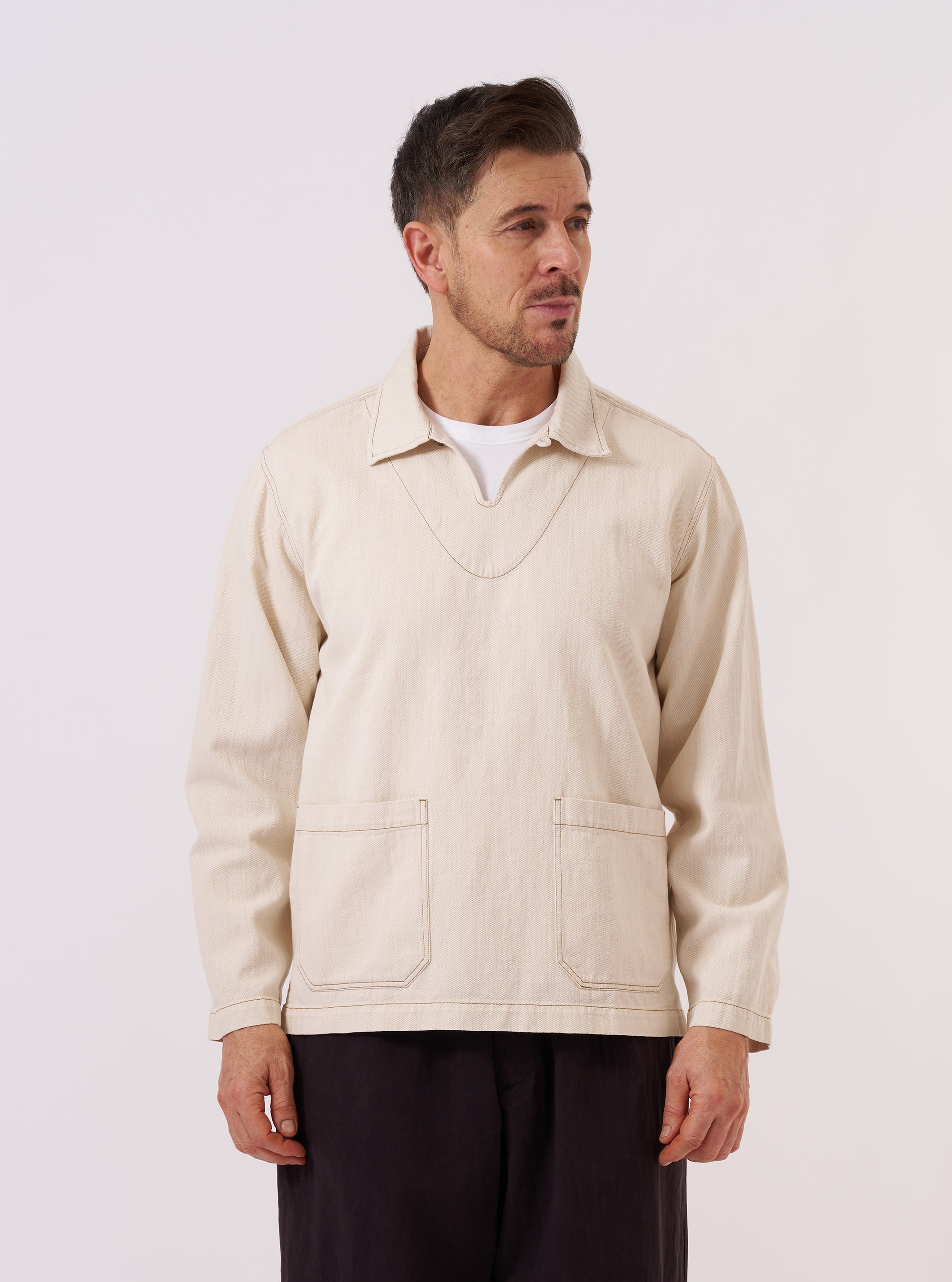 A model wears the Ecru Koko Cotlin Smock Overshirt against a plain white background. The garment features a pullover design with a partial button placket, a classic collar, and is made from a textured cotton-linen fabric in an off-white ecru shade.